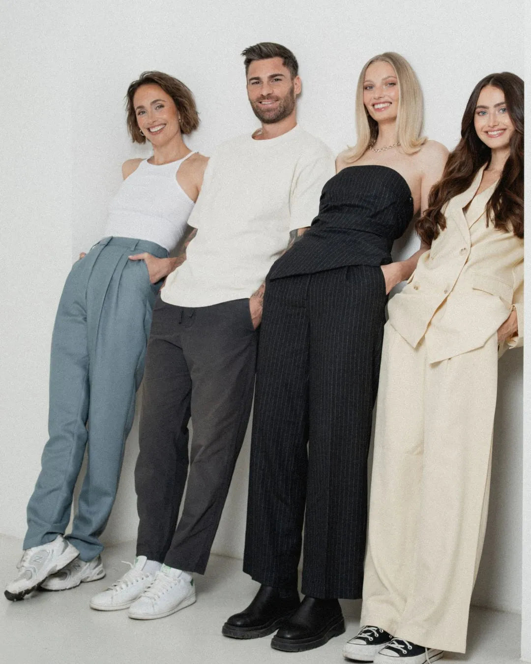 Gruppe aus drei Frauen und einem Mann steht nebeneinander und lehnt mit dem Rücken an der Wand