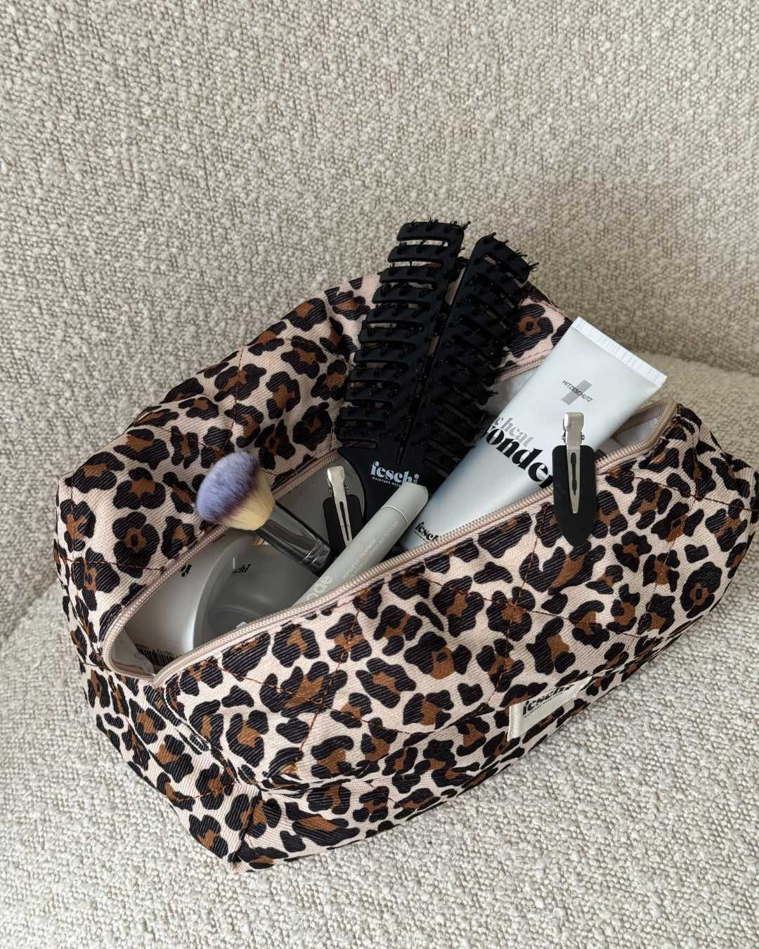 Kosmetiktasche von feschi im Leomuster mit feschi Produkten und anderen Beauty-Produkten gefüllt