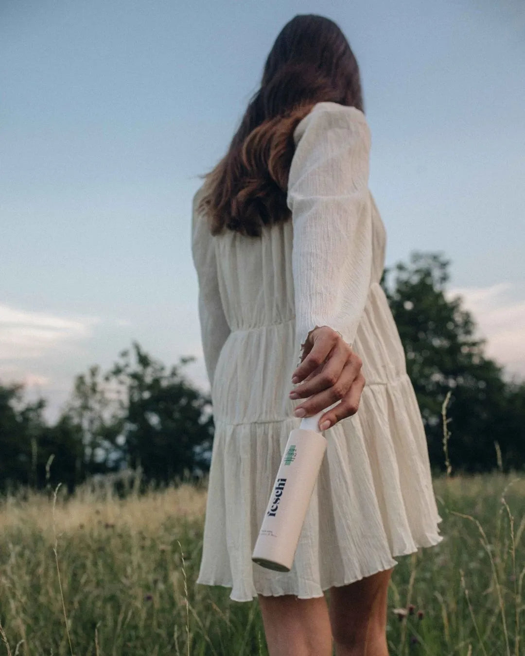 Frau geht auf Wiese und schwingt dabei das grow strong - Follicusan Shampoo von feschi in der Hand