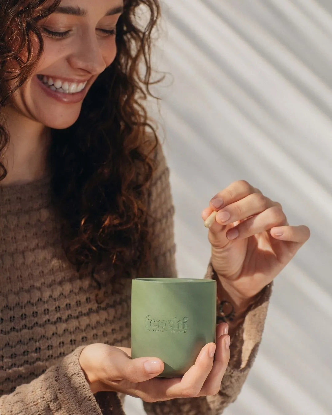 Eine Frau nimmt gerade ein feschi Hair Growth Supplement aus dem feschi Keramiktiegel heraus