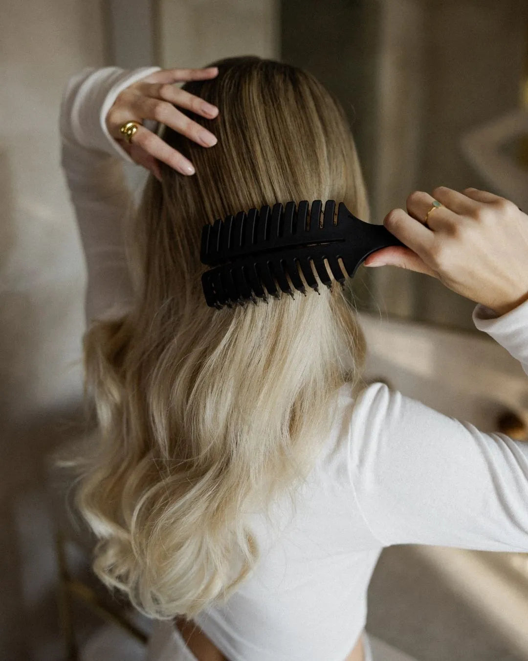 Blonde Frau bürstet sich mit der feschi Hair Brush die Haare
