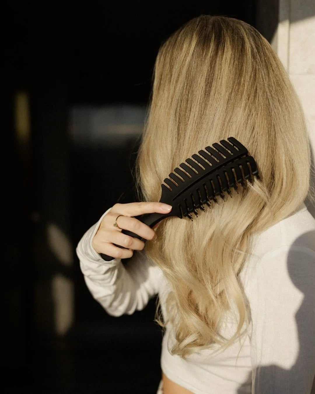 Blonde Frau, die sich mit der Hair Brush von feschi die Haare bürstet