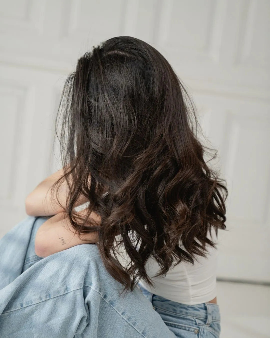 Frau sitzt auf Boden und man sieht ihr Gesicht nicht, da ihre braunen Haare es verdecken