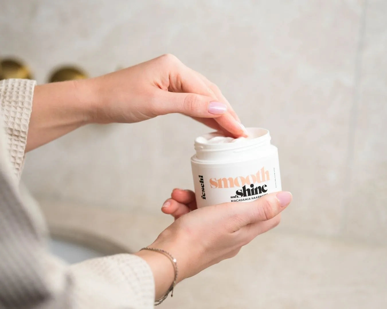 Zwei weibliche Hände, eine nimmt Produkt aus der feschi Smooth & Shine Maske