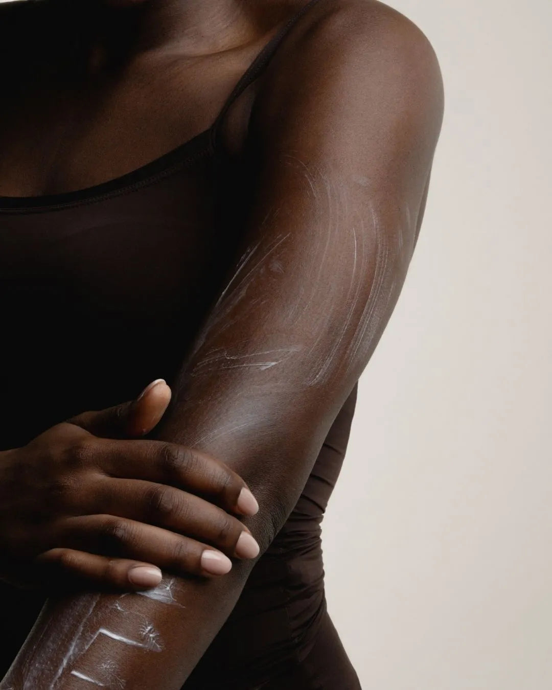 Nahaufnahme einer dunklen Haut, die mit feschi Body Lotion eingecremt wird - feuchtigkeitsspendend & pflegend.