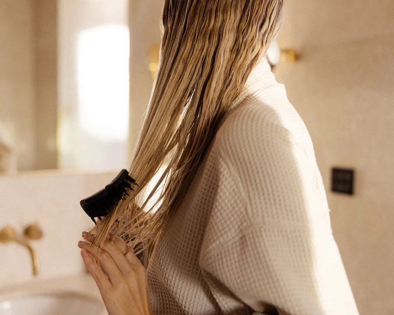Frau bĂŒrstet sich ihre nassen Haare