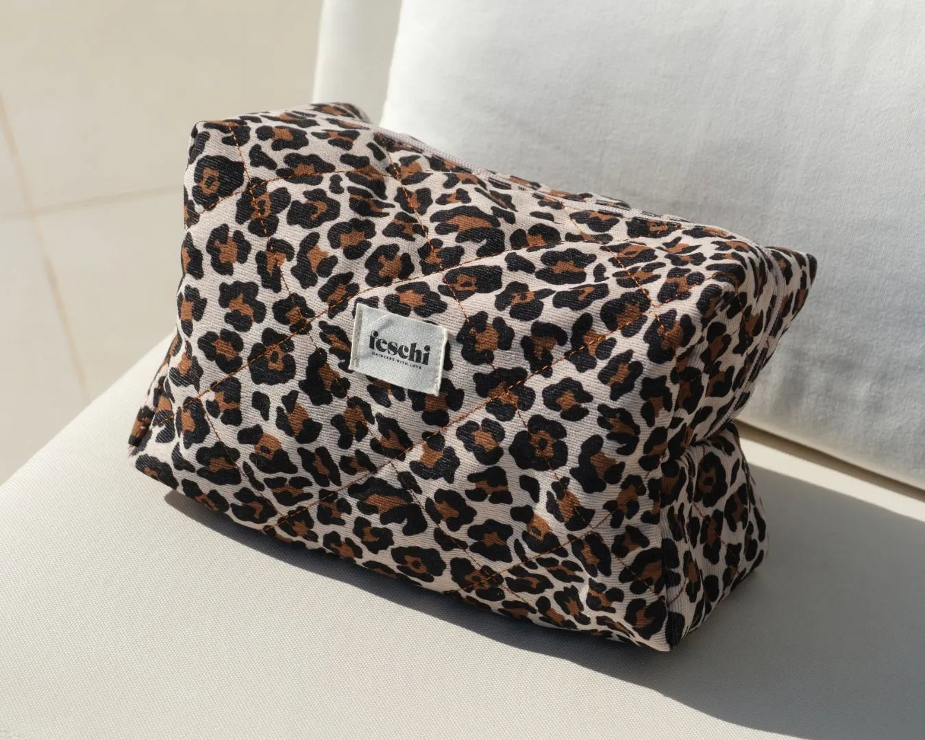 Kosmetiktasche mit Lepard Muster von feschi steht auf hellbeiger Fläche