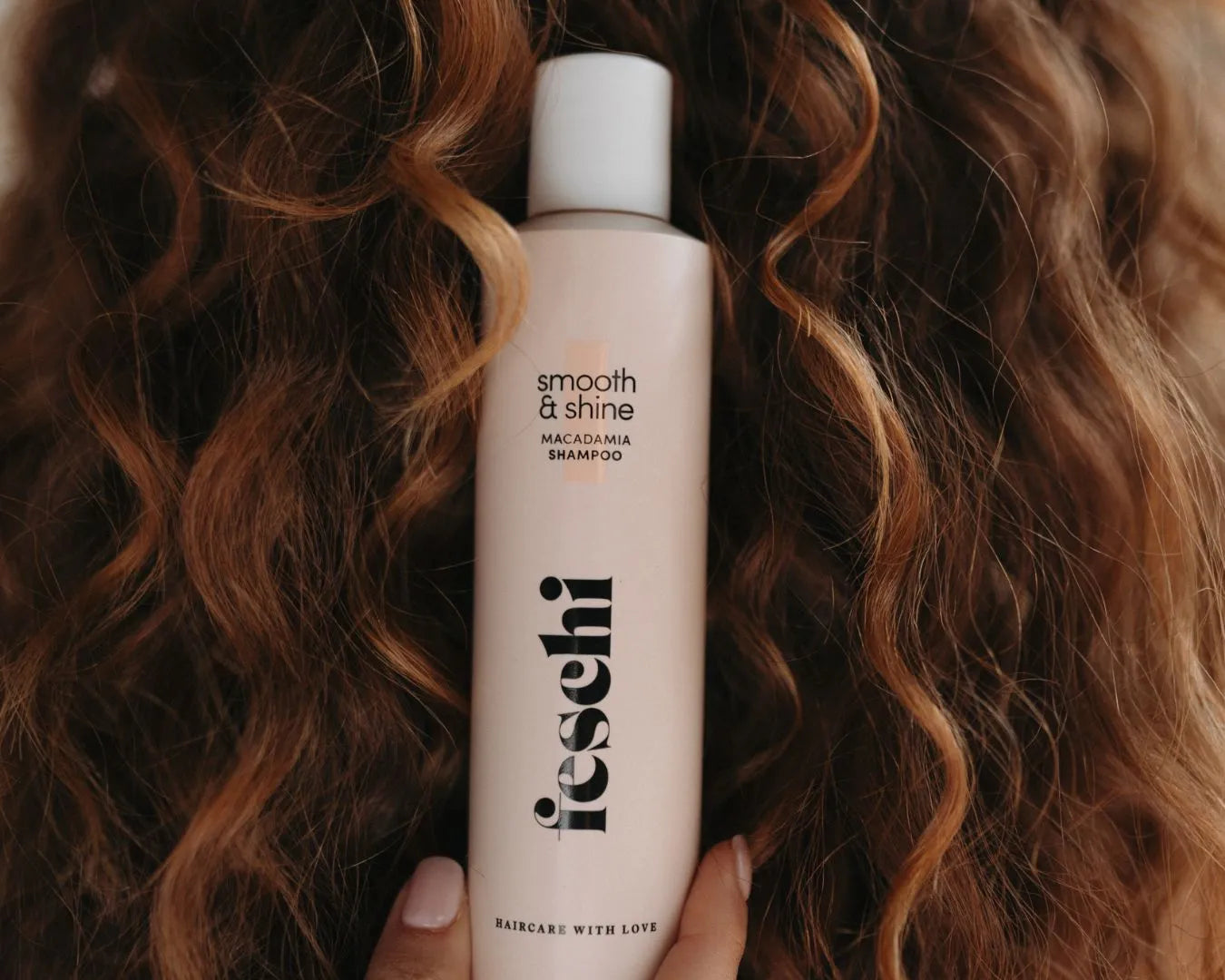 Ausschnitt vom smooth & shine Shampoo von feschi vor gelockten Haaren