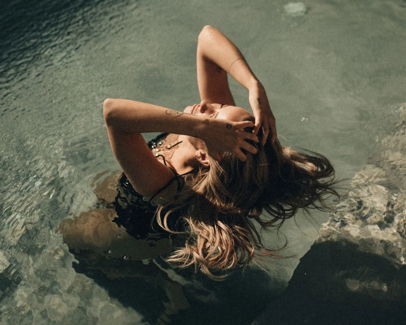 Frau in Pool macht sich die Haare nass