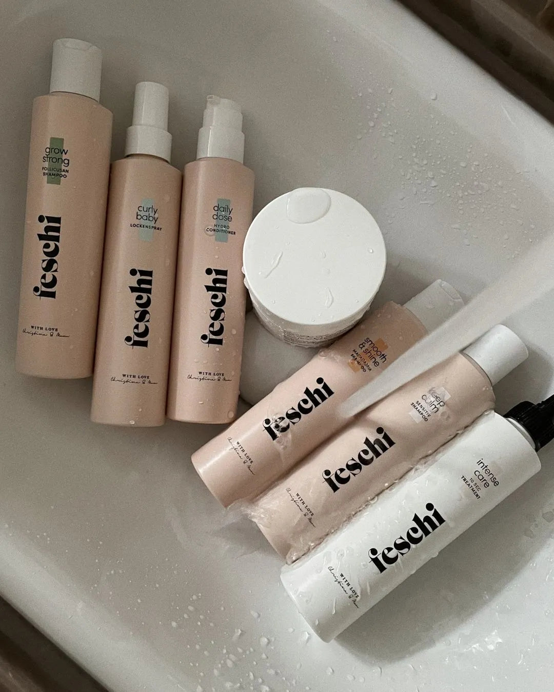 Sieben feschi-Produkte liegen in einem Waschbecken, Wasser läuft darüber