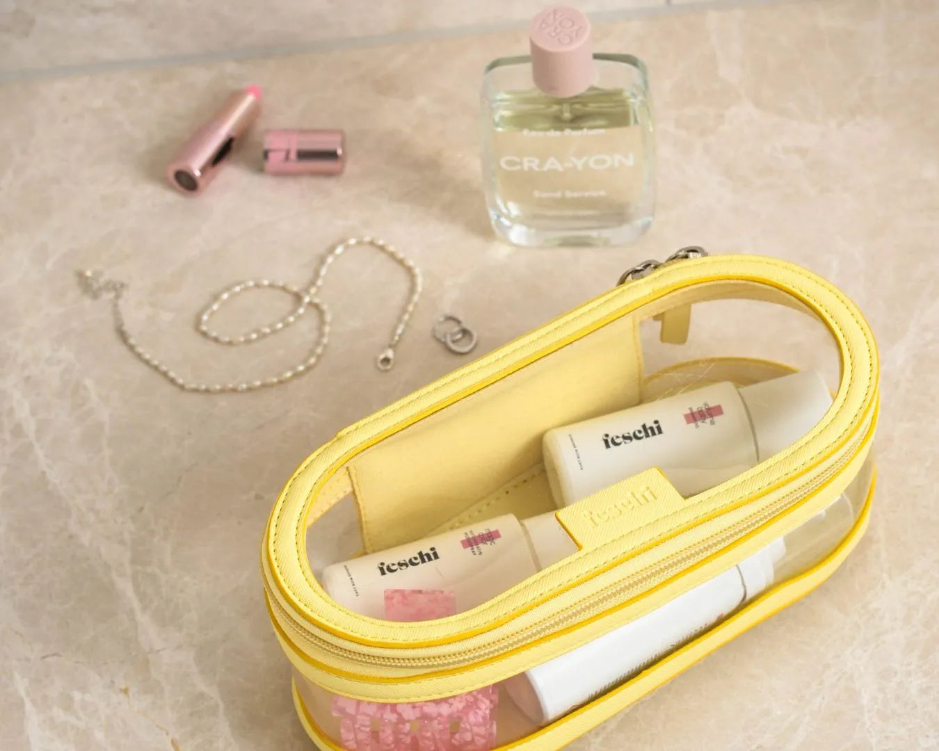 gelbe Kosmetiktasche mit feschi Produkten drinnen und anderen Beautyprodukten daneben