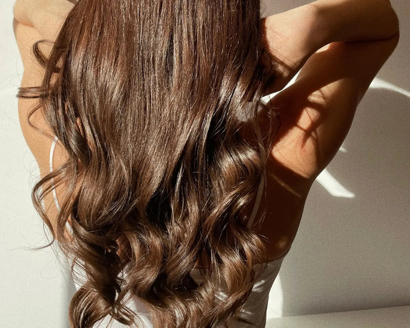 Frau von hinten mit langen, braunen, gewellten Haaren