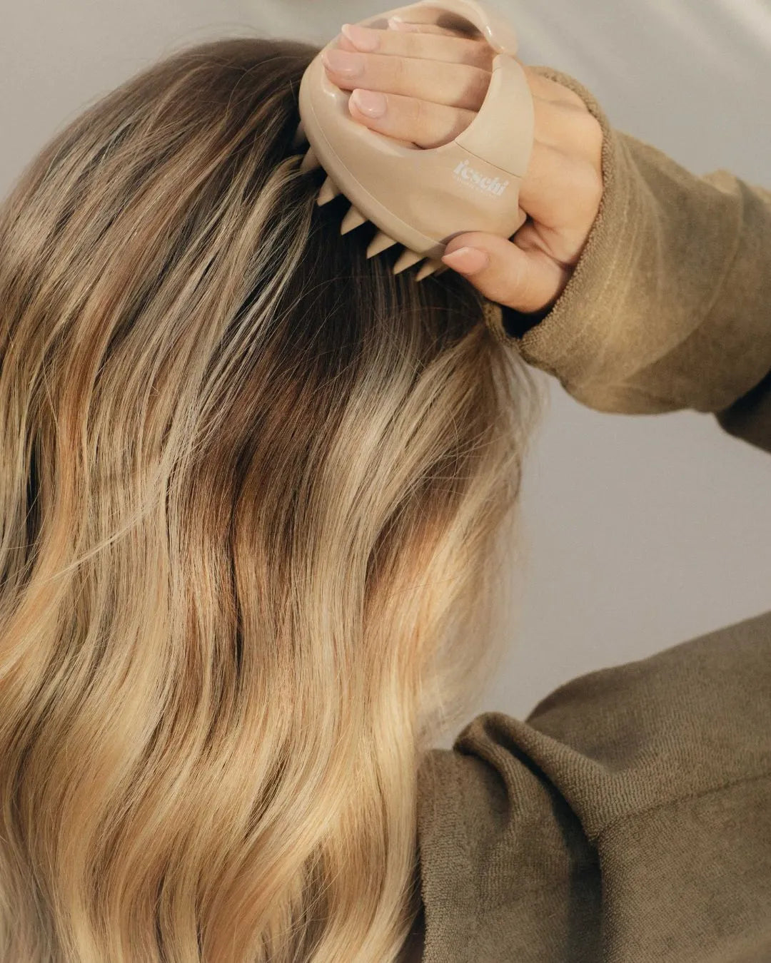 Frau mit dunkelblonden Haaren massiert ihre Kopfhaut mit der feschi Scalp Brush