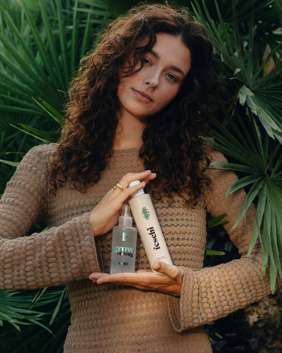 Frau mit lockigem Haar prÀsentiert die feschi grow strong Produkt mit Follicusan gegen Haarausfall.