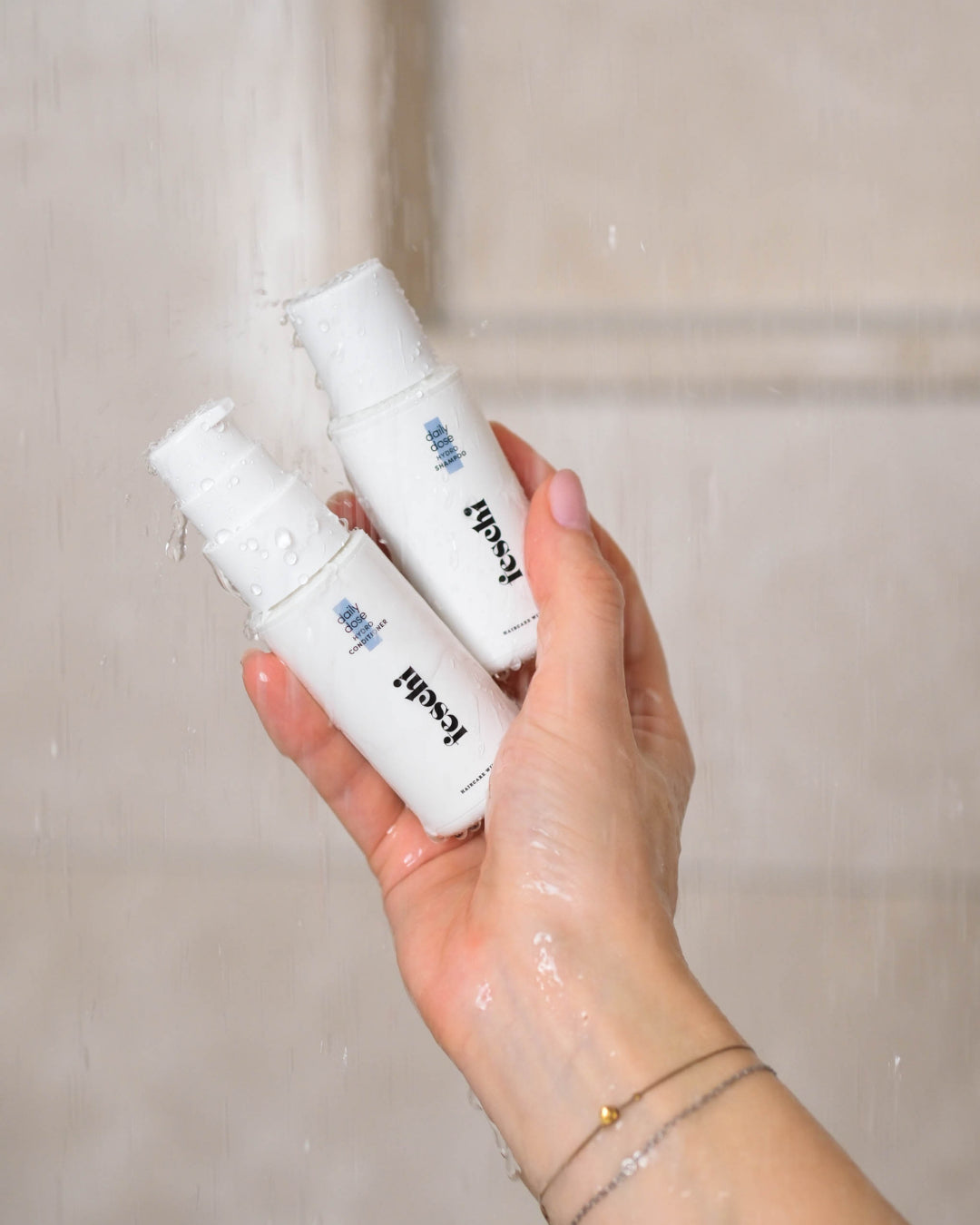 Zwei feschi Produkte in Reisegröße in der Dusche halten und Wasser fließt darauf