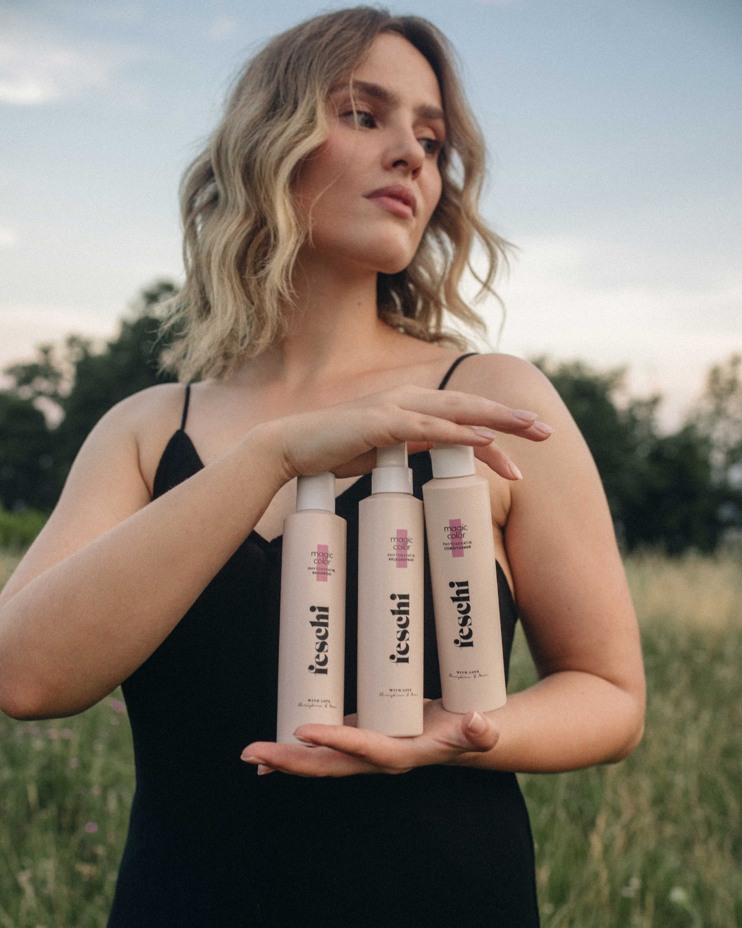 blonde Frau steht auf grünem Feld und präsentiert die feschi intense care Produktserie - perfekt geeignet für stark strapaziertes Haar.