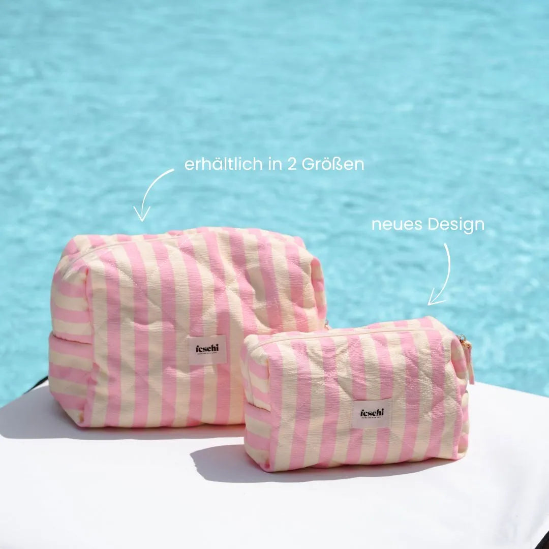 Zwei Kosmetiktaschen von feschi stehen vor Pool