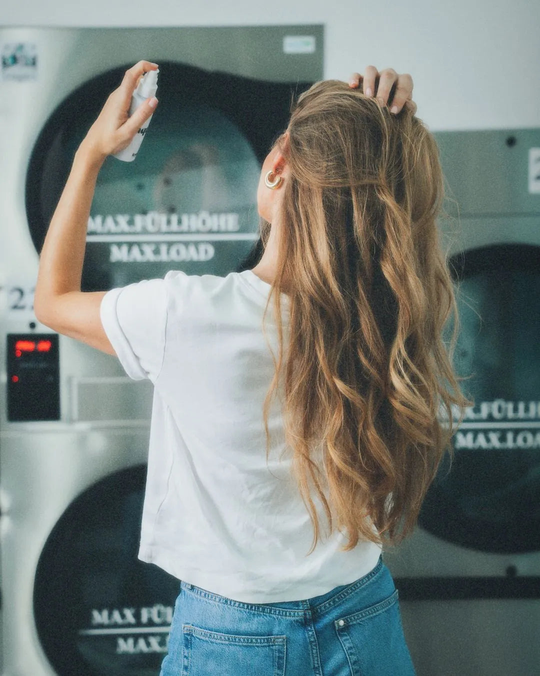 Frau sprüht sich feschi aqua dry - Trockenshampoo Liquid in die Haare