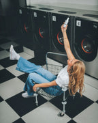 Frau sitzt in Rollwagen im Waschsalon und hält das Aqua Dry von feschi in die Luft