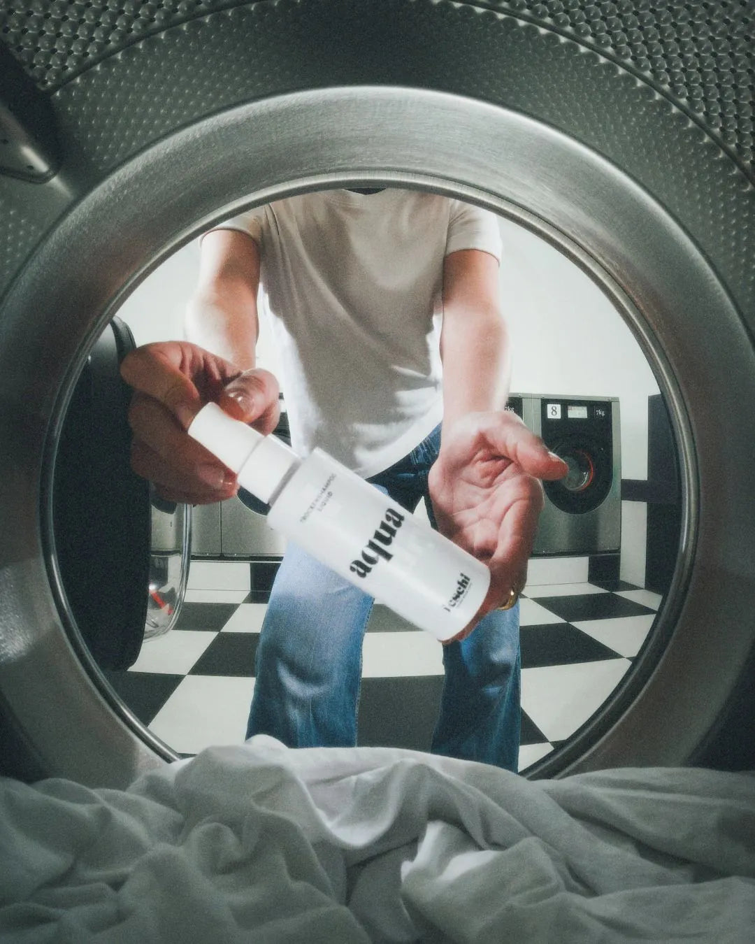 Foto von Innenseite aus Waschmaschine, wo das Aqua Dry Trockenshampoo von feschi gehalten wird