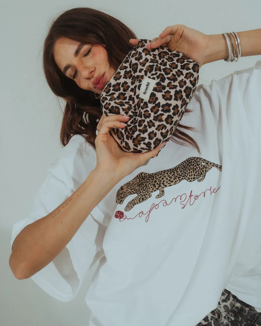 Frau hält die Little Leopard Beauty Bag von feschi in der Hand und macht einen Kussmund