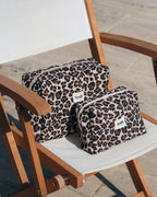 Zwei Leopard Beauty Bags von feschi in unterschiedlichen Größen stehen auf Stuhl