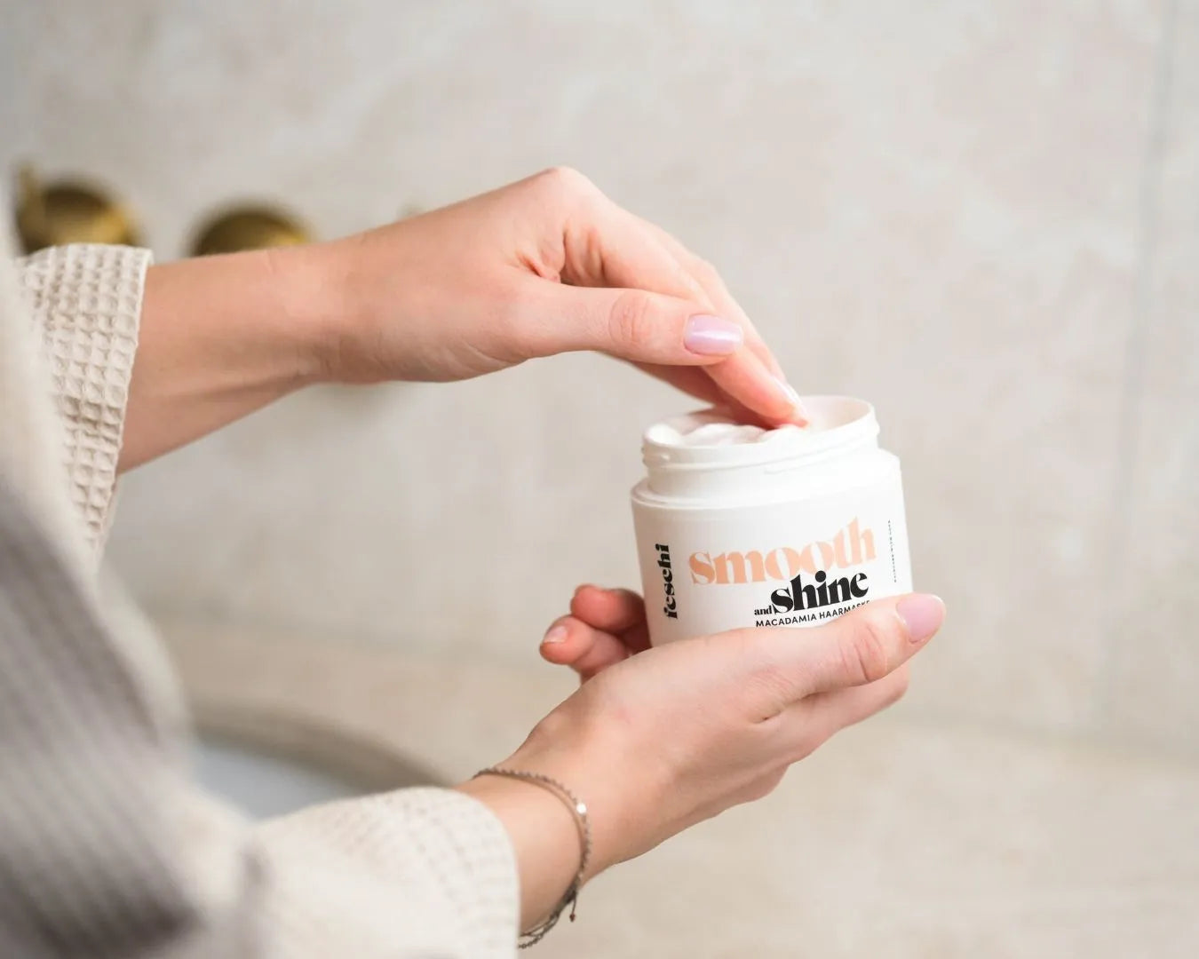 Person hält smooth & shine - Macadamia Maske von feschi in der Hand und holt sich was aus der Tube