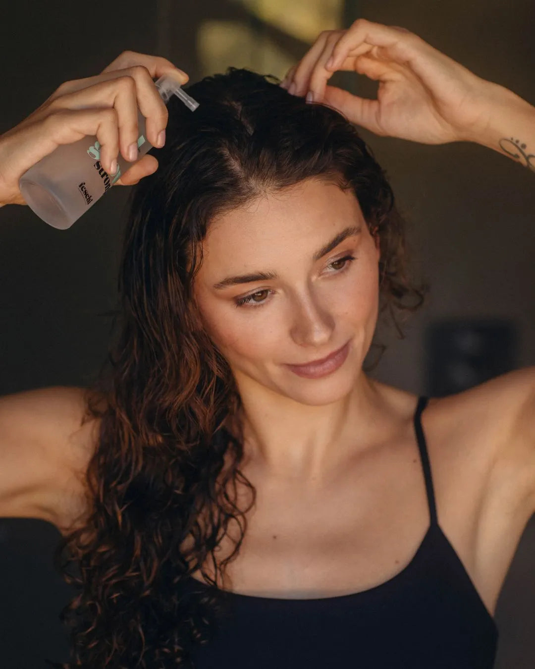 Frau mit braunen, lockigen Haaren verwendet grow strong Tonic von feschi