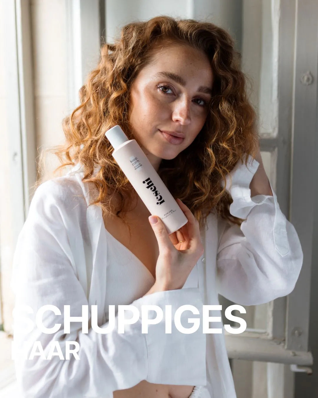 rothaariges, lockiges Model lächelt in die Kamera und hält das feschi keep calm Sensitiv Shampoo in ihrer Hand