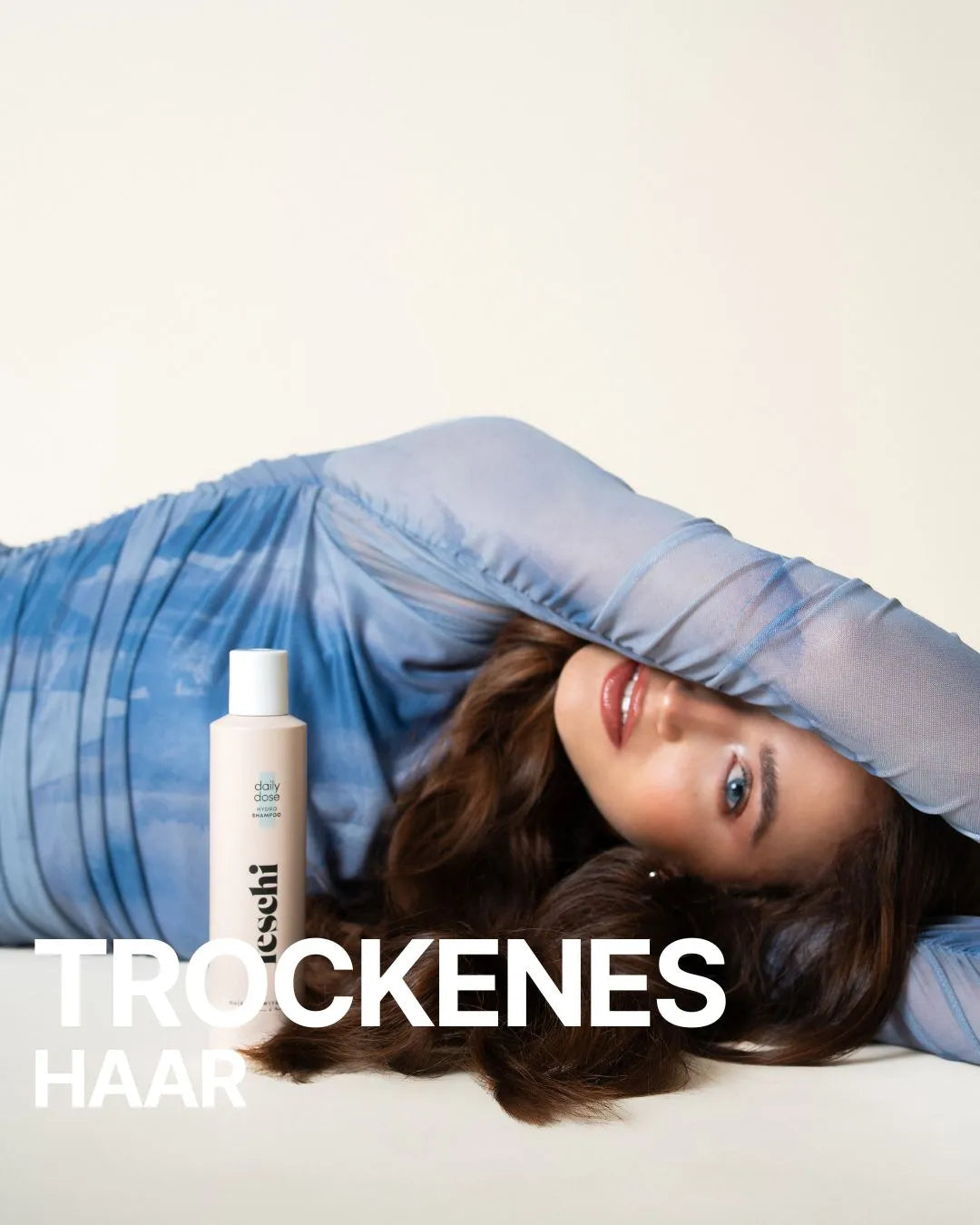 braunhaarige Frau liegt am Boden und feschi daily dose Shampoo steht vor ihrem Körper