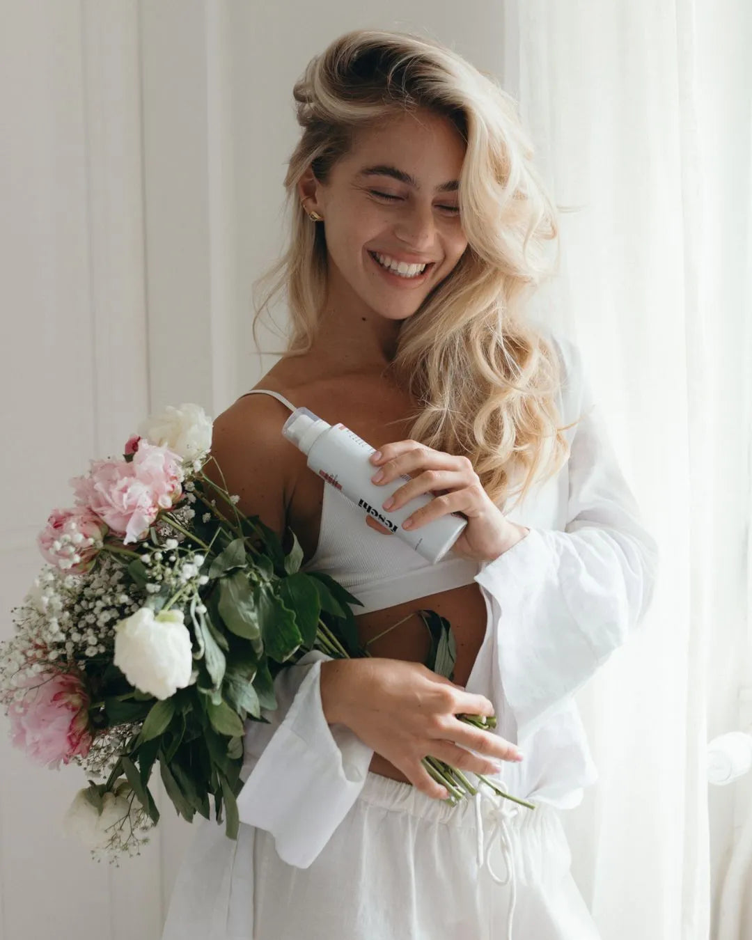 Frau hält Blumenstrauß in der Hand und den Trockenshampoo Schaum von feschi. Dabei lächelt sie