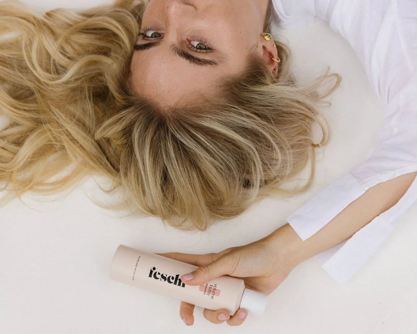 Frau liegt im Bett und hält das feschi Volume Baby Shampoo in der Hand