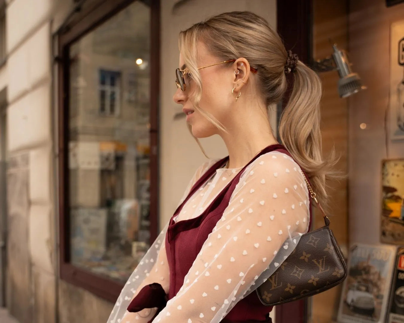 Frau seitlich, im Dirndl, mit dunkelblonden Haaren zu einem Zopf gebunden, steht vor einem Schaufenster