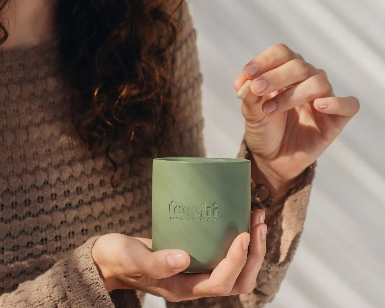Zwei Hände, eine hält den feschi Grow Strong Tiegel, die andere nimmt das Hair Growth Supplement daraus