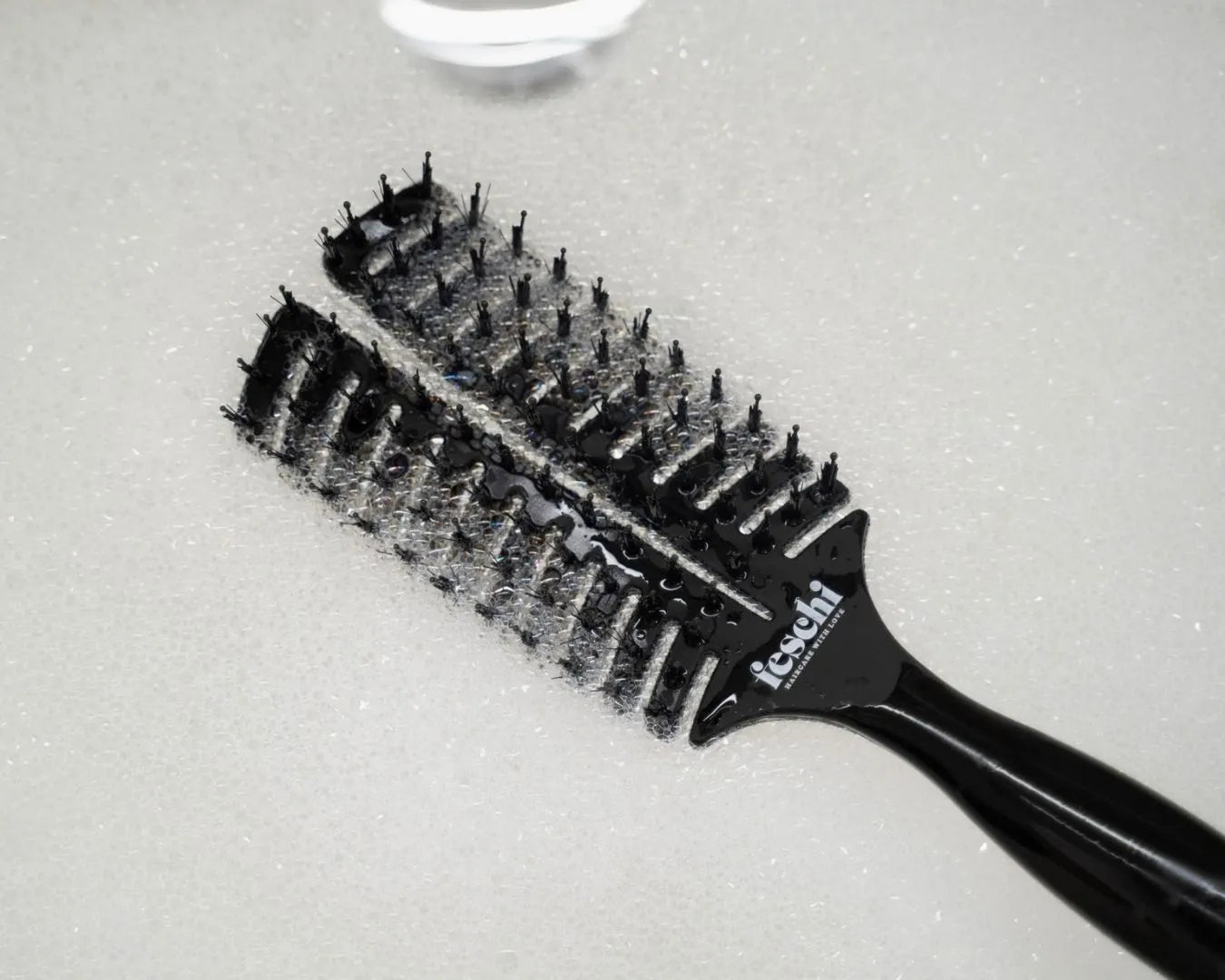 Haarbürste im Schaumbad im Waschbecken