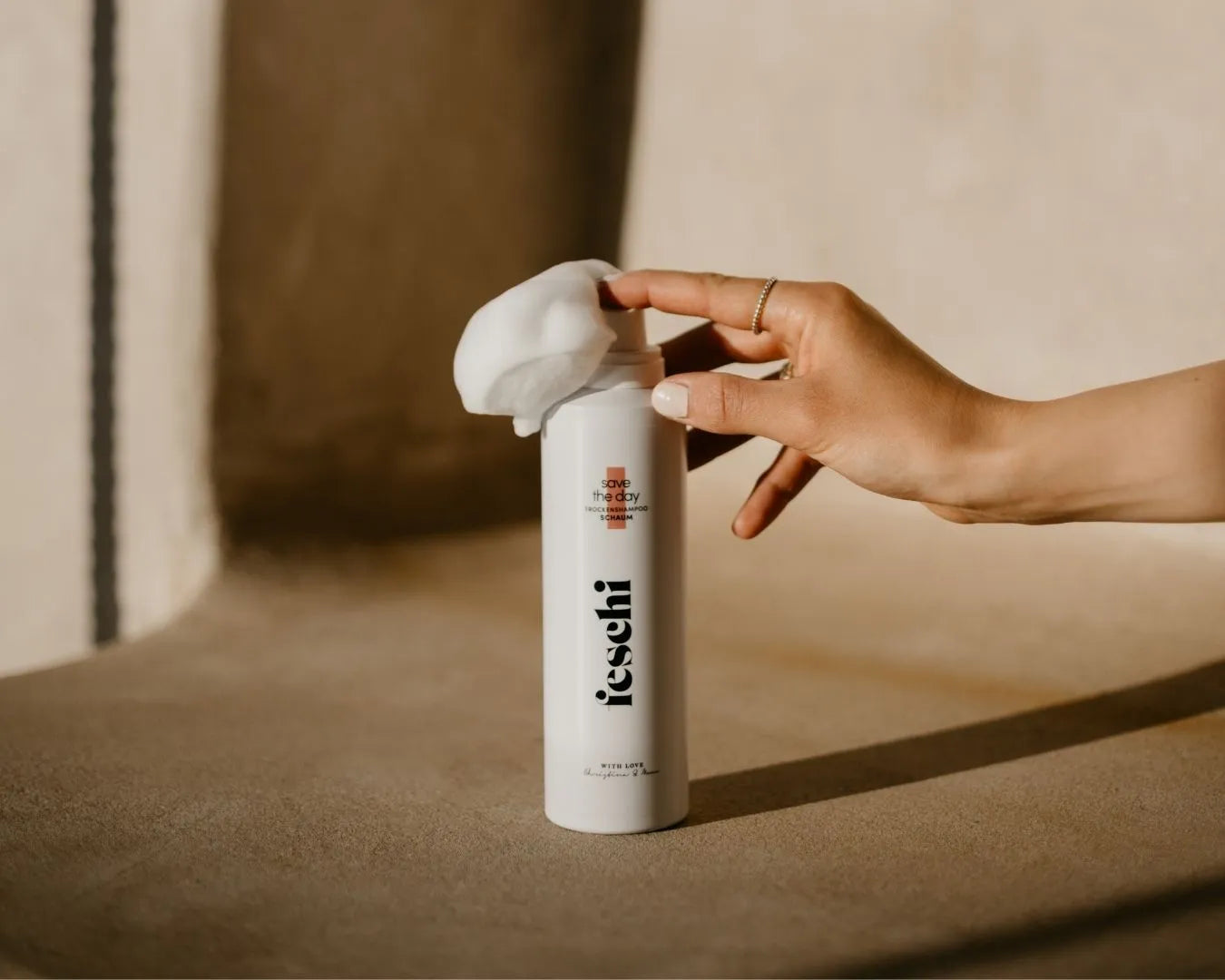 Hand drückt auf das feschi Save the Day Trockenshampoo-Schaum, Schaum tritt aus