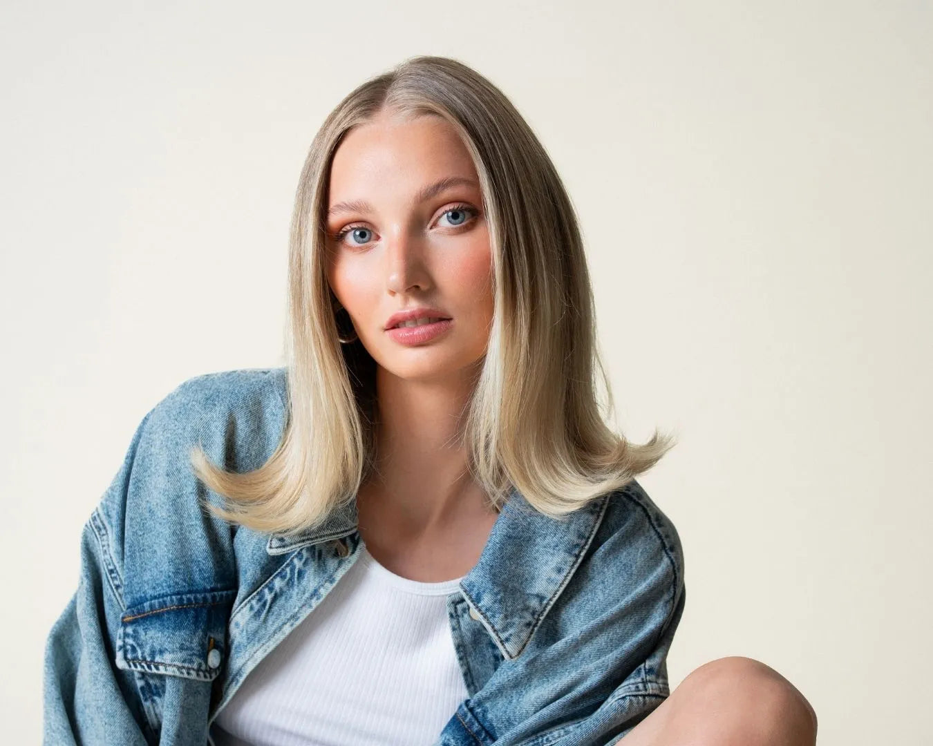 Blonde Frau mit Jeansjacke schaut in Kamera