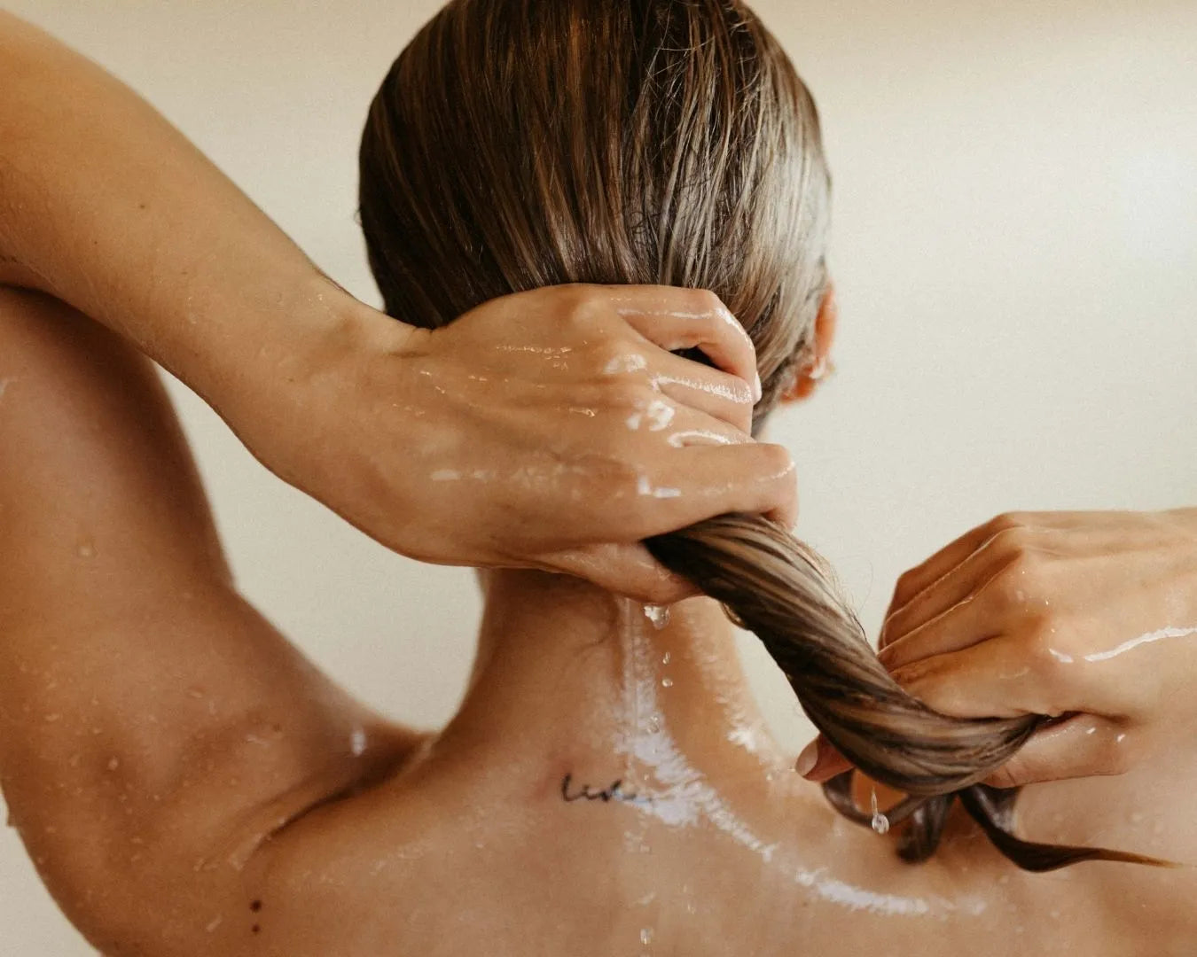 Frau von hinten, die sich gerade die Haare wäscht