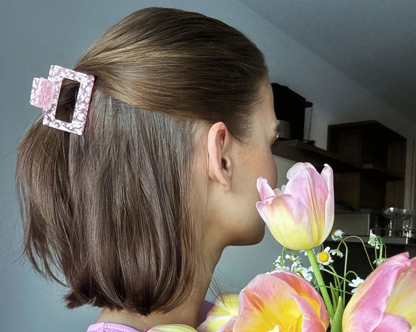 Frau mit schulterlangen Haaren und rosa Haarspange seitlich zu sehen