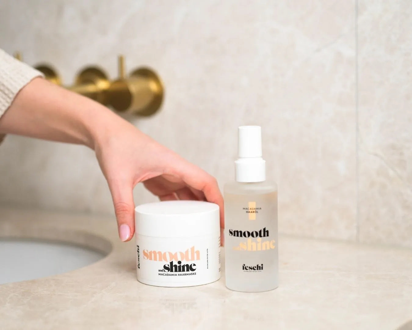 Weibliche Hand greift zur feschi Smooth & Shine Macadamia Maske, daneben steht das Smooth & Shine Haaröl