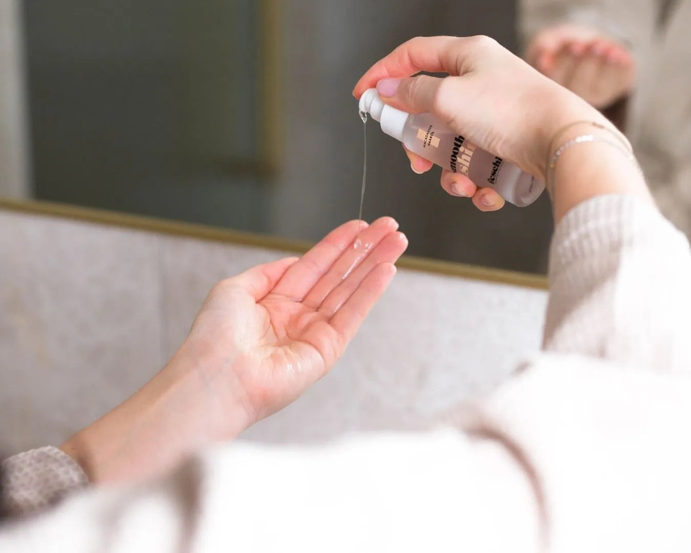 Weibliche Hände, eine Hand hält das feschi Smooth & Shine Haaröl und drückt das Produkt in die andere Hand