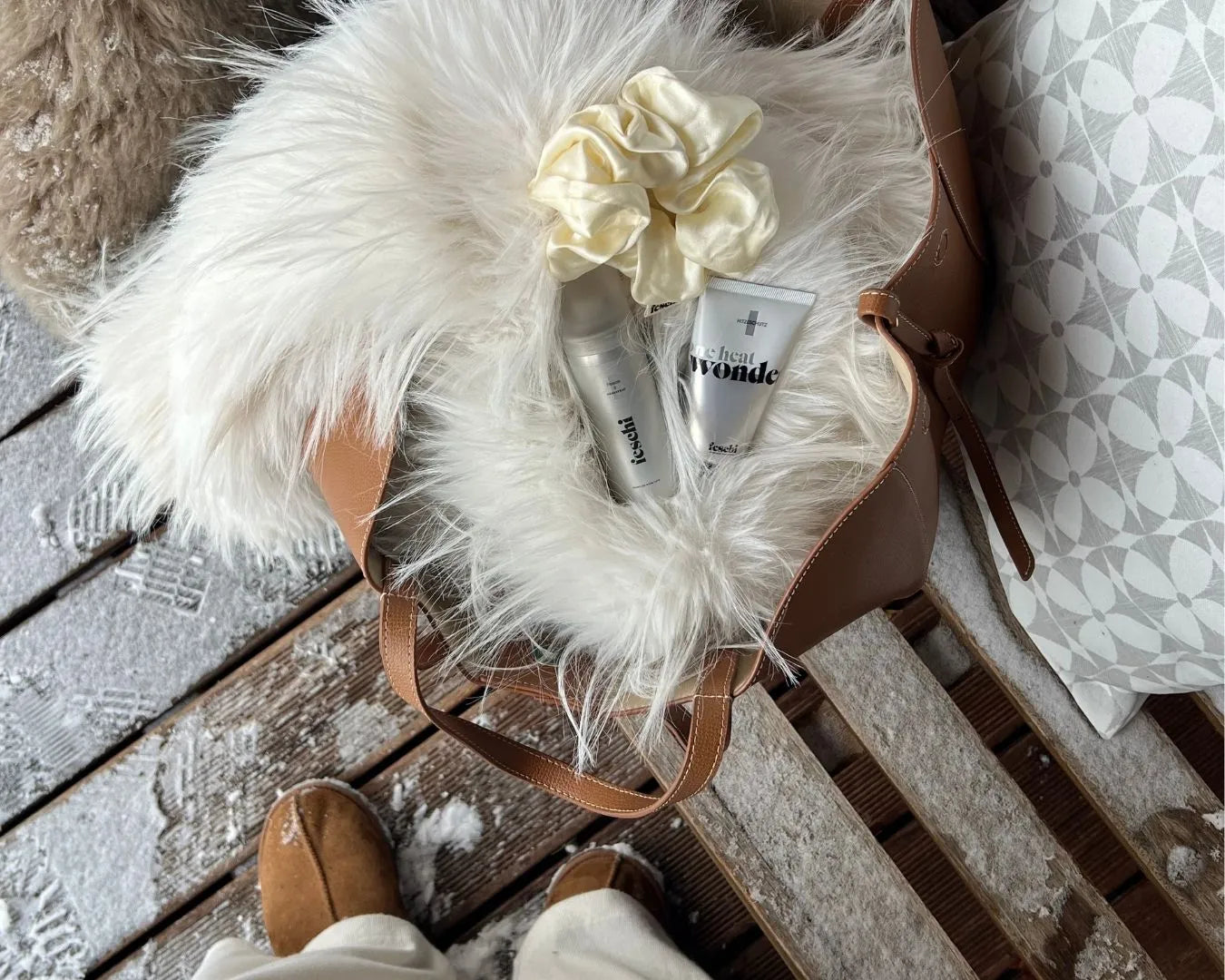 Flatlay von Tasche mit Fell und feschi Haircare Produkten darin