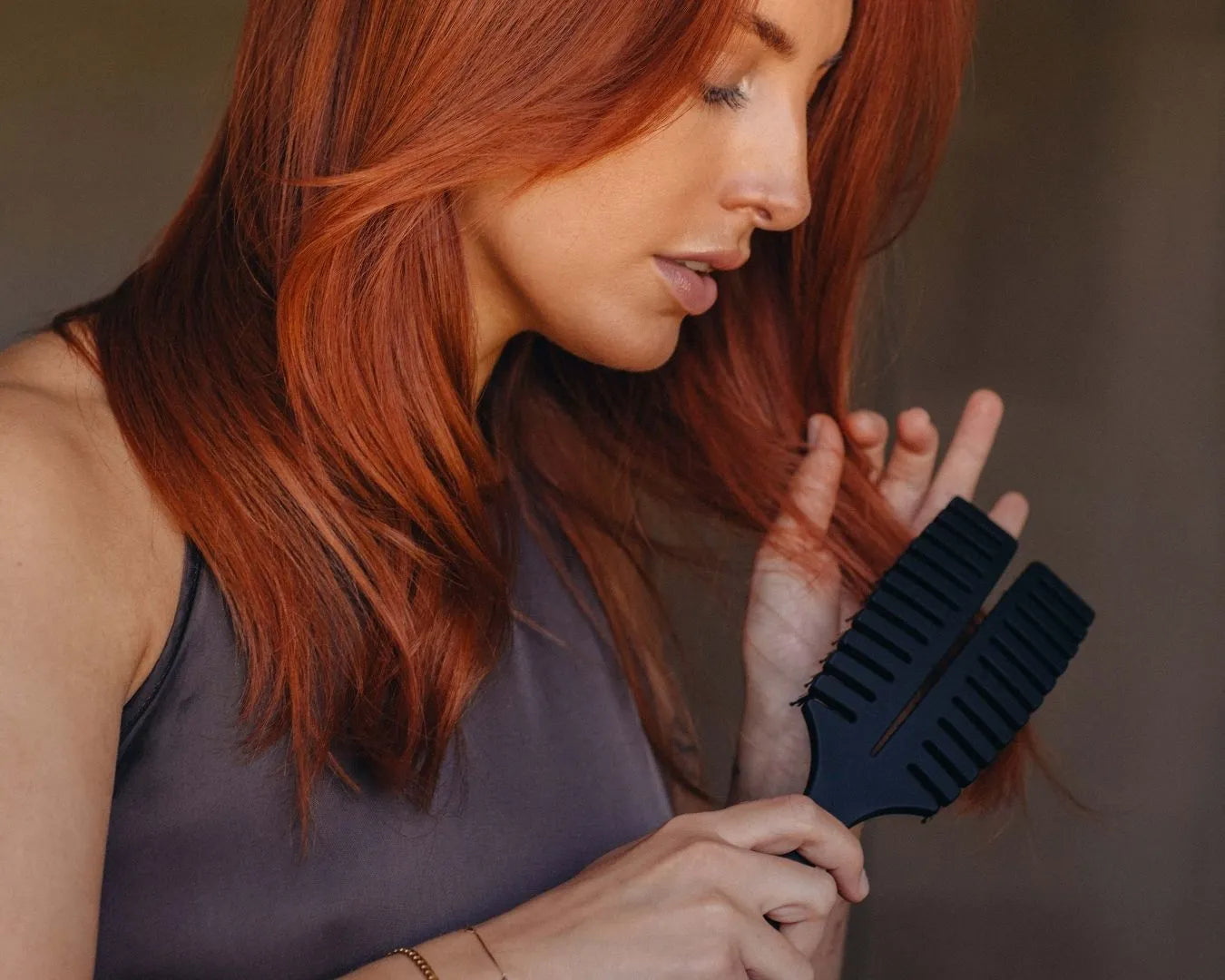 Frau mit rötlichen Haaren kämmt sich behutsam die Haare mit einer schwarzen Fingerbrush von feschi