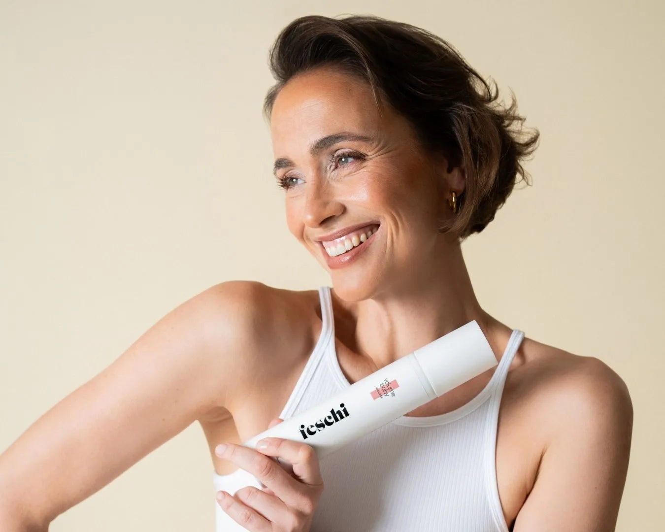 Frau lächelnd mit kurzen braunen Haaren hält das feschi Volume Baby Mousse in der Hand