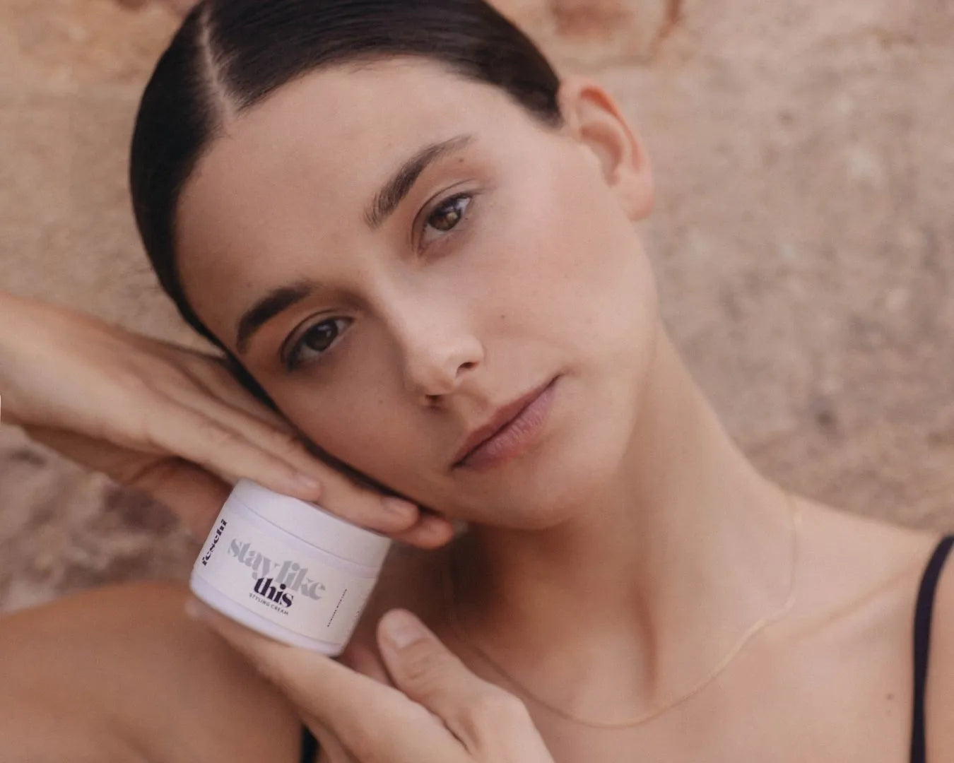 Frau hält Styling Creme von feschi und trägt einen Sleek Look