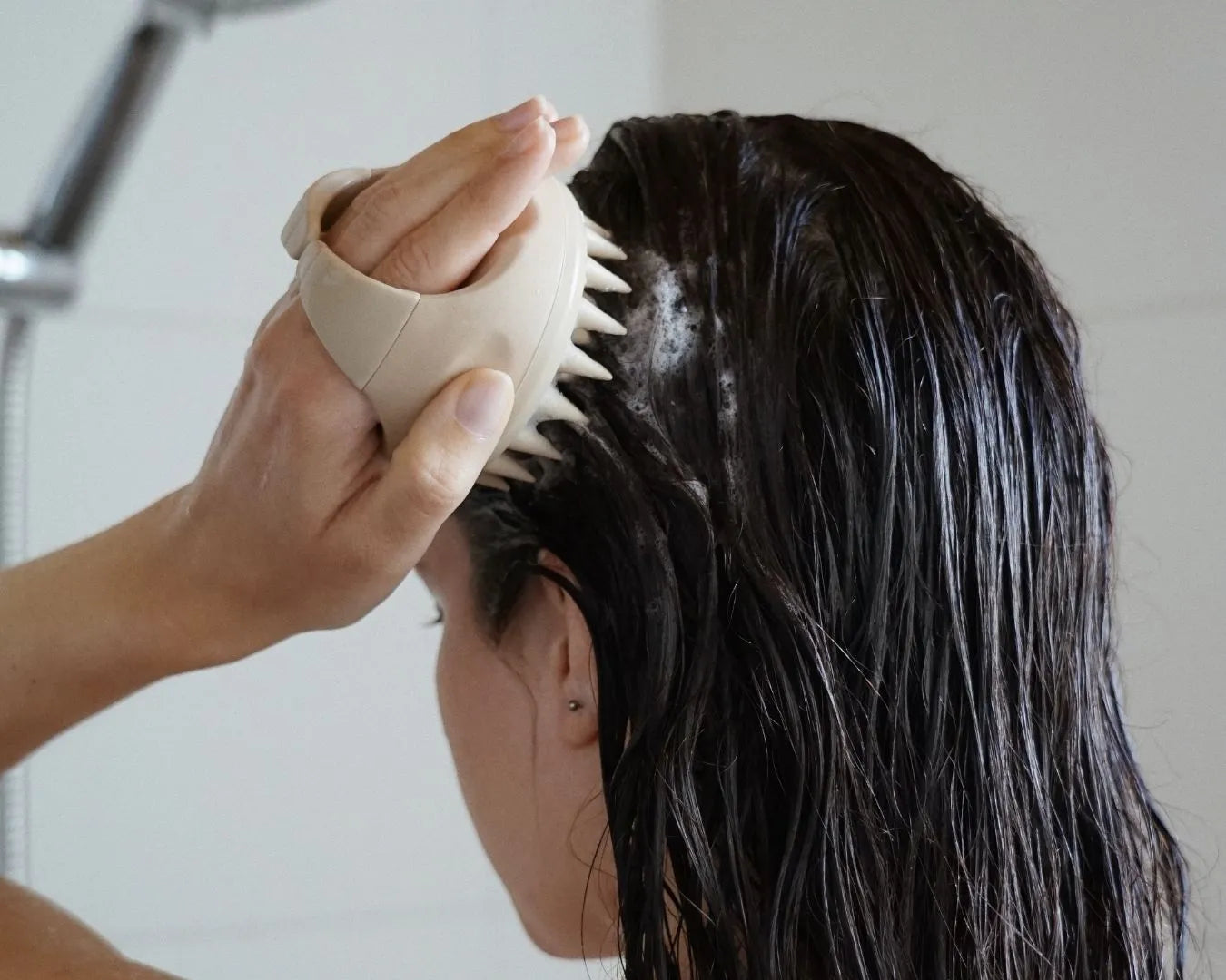 Person massiert in der Dusche das Shampoo mit einer scalp brush von feschi ein