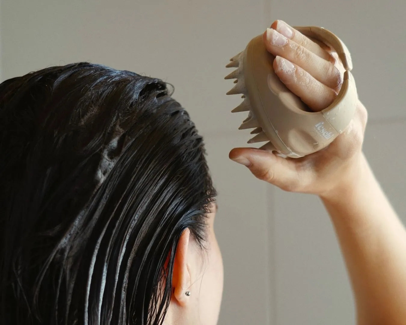 Frauenkopf mit dunklen, nassen braunen Haaren, nutzt die feschi Scalp Brush