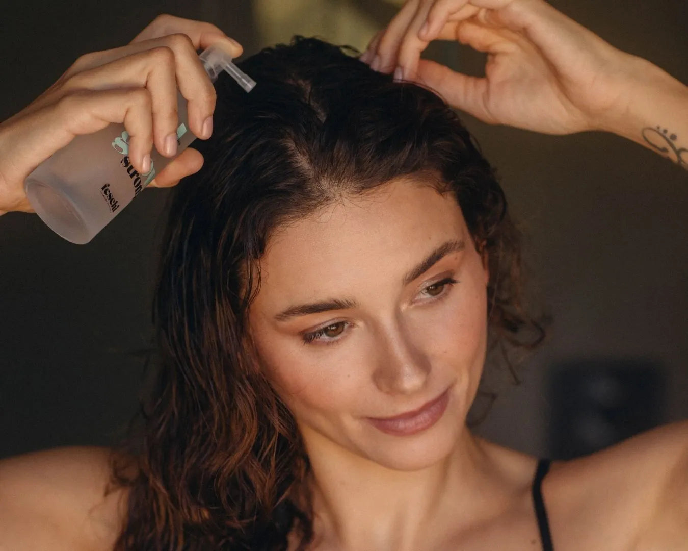 Frau mit langen braunen Haaren trägt das feschi Grow Strong Follicusan Tonic am Haaransatz auf