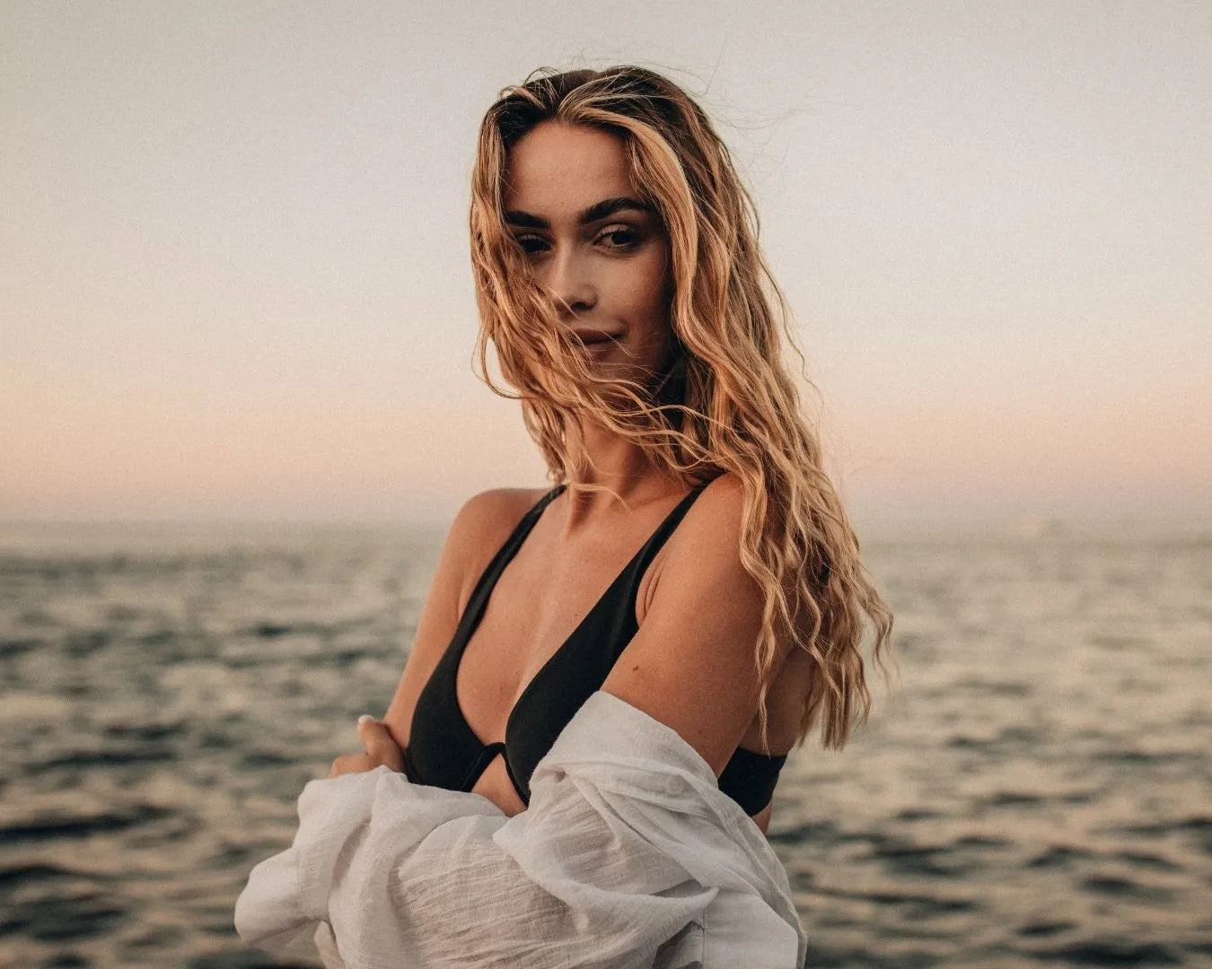 Frau mit Beachwaves steht vor dem Meer