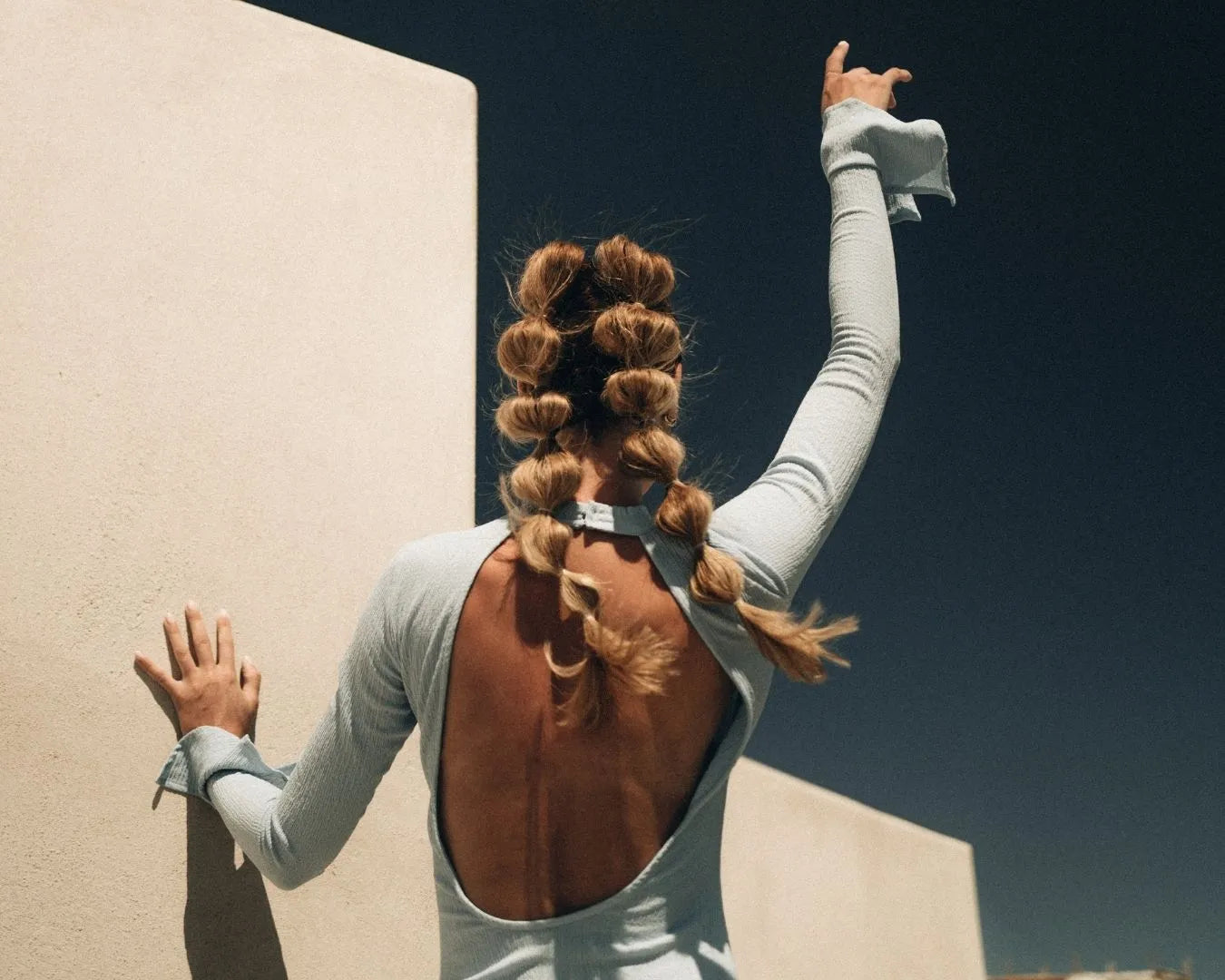 Person mit Bubble Braids und einem blauen Kleid von hinten zu sehen